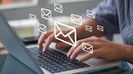 Person is typing on a laptop surrounded by email icons