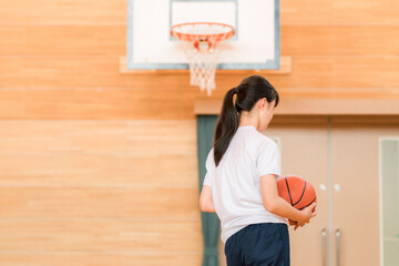 体育館でバスケットボールを持つ体操着姿の女子中学生・女子高生
