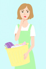 pensive young woman is thoughtfully holding a laundry basket filled with clothes