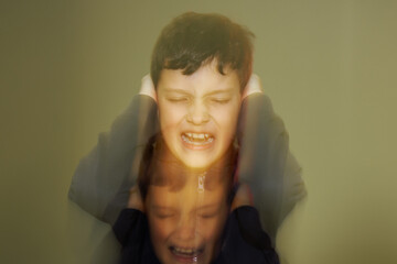 A teenager boy is holding his ears and screaming of negative emotions, anger and pain. Reflection of his face like a soul. © Saeedatun