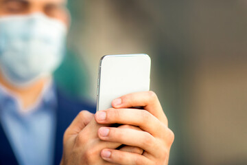 Modern smartphone in arabic businessman hands, man wearing protective face mask, entrepreneur, independent contractor working online while COVID-19 pandemic, copy space. Technologies in business