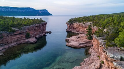 Fototapeta premium Stunning Aerial View of Rocky Cliffs and Serene Waters Surrounded by Lush Green Forests