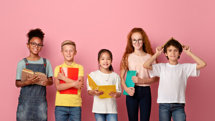Multinational group of kids with books and notebooks ready for school over pink studio background