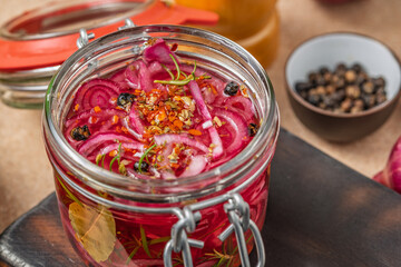 Homemade pickled red onions in a glass jar with spices and herbs. Close-up of a fermented food, perfect for healthy eating and gourmet recipes.