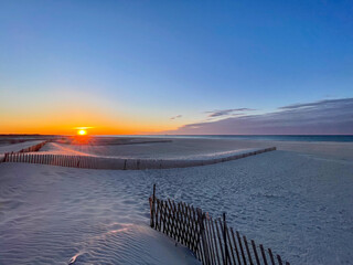 Gorgeous Orange Sunrise on white sand beach with barrier at the front, little cloud in the side  in Long Island NY, USA - concept of nature, 