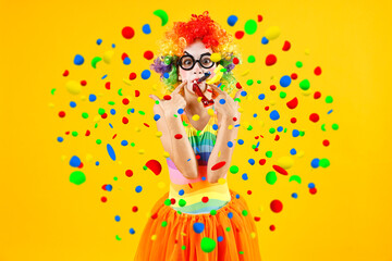 Girl dressed like clown with party blowers under falling confetti on orange background