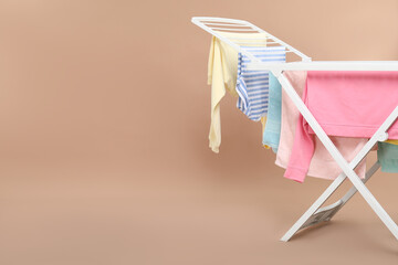 Drying rack with fresh clean laundry on beige background. Space for text