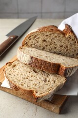 Cut loaf of fresh bread and knife on table, closeup