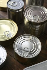 Many closed tin cans on wooden table, closeup