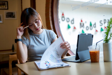 A woman is sitting at a table with a laptop and a piece of paper