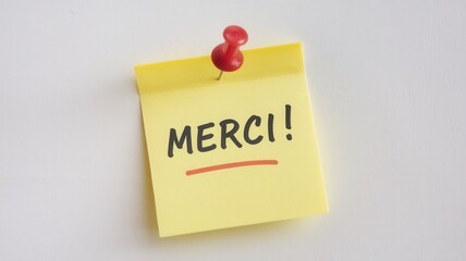 A yellow sticky note saying merci pinned to the wall