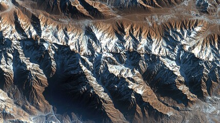 Aerial view of rugged mountain terrain showcasing snow-capped peaks and deep valleys