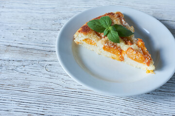 Slice of peach pie on a white plate on a wooden background