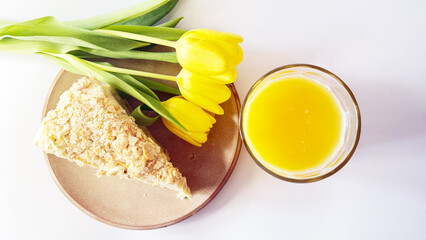 This photograph showcases a slice of Napoleon dessert cake with flaky layers and creamy filling, served on a wooden plate. The cake surface is sprinkled with delicate pastry crumbs, highlighting its
