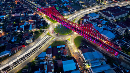 The beautiful night view of Joglo Underpass Roundabout in Solo shows busy traffic with cars and a...