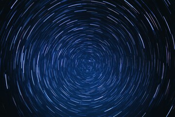 This mesmerizing image captures swirling star trails against a deep blue sky. The long exposure technique highlights the motion of stars, creating a sense of cosmic dance and tranquility.
