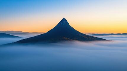 Fototapeta premium Breathtaking Sunrise View of Mountain Peak Emerging from Soft Layers of Fog and Clouds
