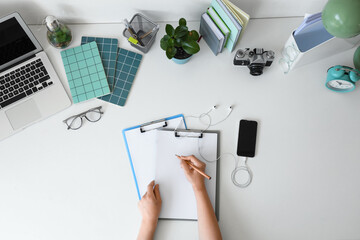 Woman with clipboards and office stationery on white table, top view