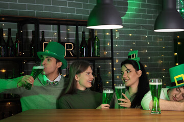 Group of drunk young people with beer celebrating St. Patrick's Day at counter in pub