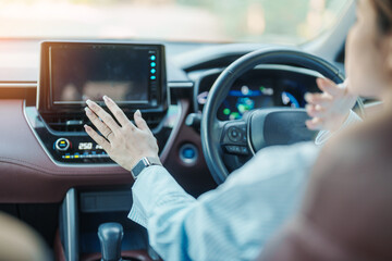 Woman hand adjusting temperature the air flowing during driving car on the road, air conditioner...