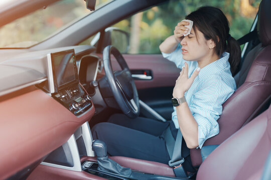 woman driving car with broken air conditioner in hot summer weather, uses tissue paper napkin to wipe the sweat off her forehead. Businesswoman driver is tired, Exhausted overheated and stressed