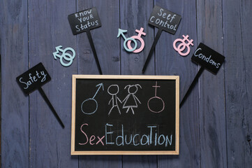 Chalkboard with written text SEX EDUCATION and cards with words on dark wooden background