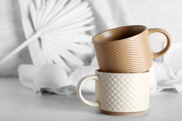 Different ceramic mugs on light background