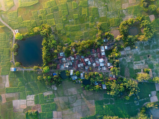 Fototapeta premium A stunning aerial shot of a quaint village waking up to the first light of the sun, with soft mist hovering over fields and houses. Ideal for countryside and lifestyle visuals.