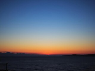 Fototapeta premium Sun setting over a tranquil lake with a silhouetted tree framing the scene, view, scenic, horizon