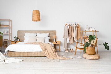 Interior of modern comfortable bedroom and rack with woman's clothes