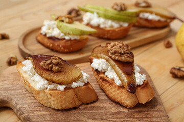 Boards of pear bruschetta with ricotta cheese and walnuts on wooden background, closeup
