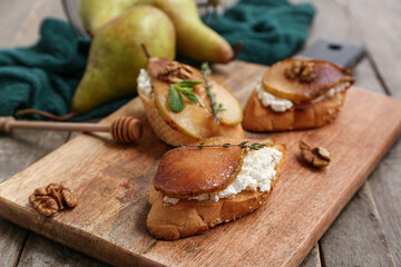 Board of pear bruschetta with ricotta cheese and walnuts on wooden background, closeup