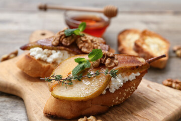 Board of pear bruschetta with ricotta cheese and walnuts on wooden background