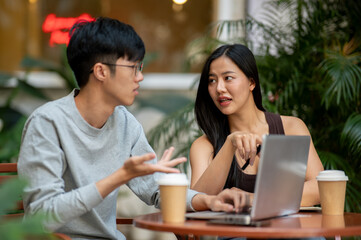 Confident Asian woman has a meeting with her colleague at a coffee shop, sitting at an outdoor table