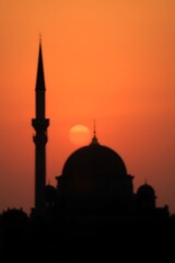 Fototapeta premium Mosque Silhouette at Sunset with Tower and Dome Against Orange Sky