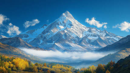 Fototapeta premium Majestic Mountain: Towering snow-capped peak under a vibrant blue sky, framed by rolling hills of autumnal trees, soft clouds, and a misty valley.