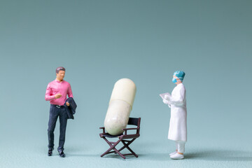 Tiny figurines of a businessman and a doctor examining an oversized capsule placed on a chair