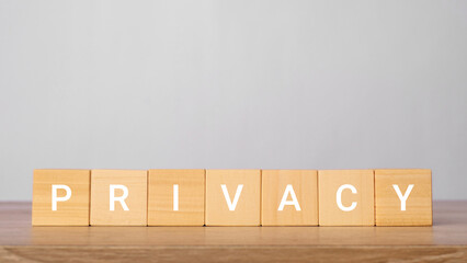 Privacy word written on wooden blocks on a wooden table with a light gray background. Data...