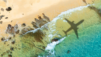 Aerial view of shadow passenger plane silhouette and sandy beach blue sea with waves at sea beach summer vacation sea travel concept	
