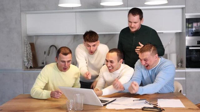 Group of men watching sports match online on laptop during friendly meeting with beer at home, excitedly celebrating winning score in game 