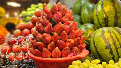 The basket in the fruit shop is filled with a pile of strawberries.