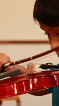 Cute pupil playing violin in classroom