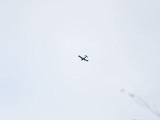 Small ultralight airplane with overhead wing and single propeller flying in sunset sky.