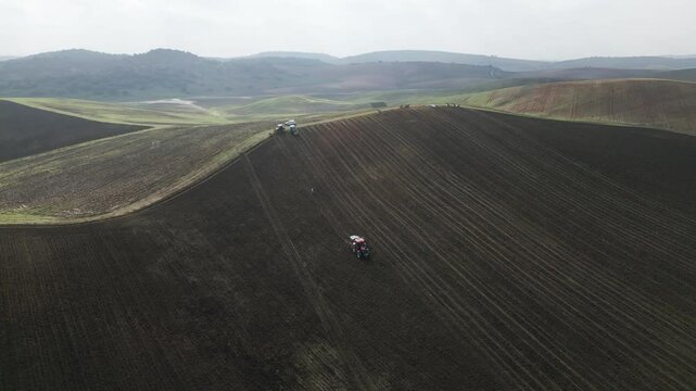 Tracor working on hilly farmland of Spain, aerial view