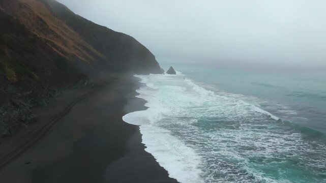 USAL Beach campground 4wd car truck tracks black sand mist rain fog Lost Coast Trail aerial drone California PNW waves crashing early morning rugged coastline Chimney Rocks circle left motion