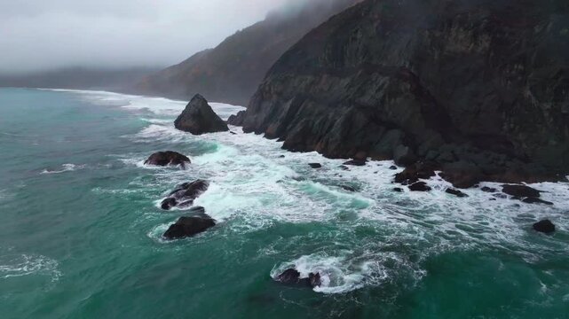 Rugged dramatic untouched coastline USAL Beach campground cloud layer mist rain fog aerial drone California PNW Lost Coast Trail morning huge surf waves boulder rocks nature landscape backwards pan up