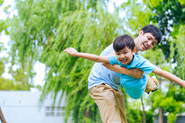 Asian boy flying by his father with fun and smile, Singgle dad play with his son at park.
