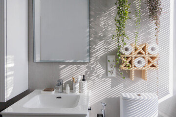 Stylish clean white bathroom with light gray tiles on the walls and lots of indoor plants.