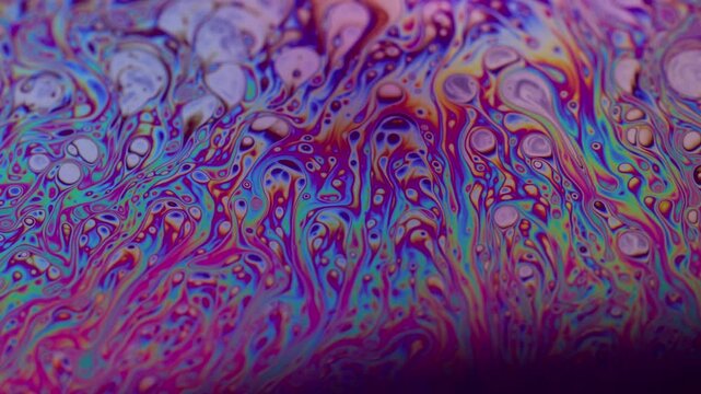 Marble texture. Fluid soap bubble. Defocused multicolor purple green liquid oil paint curve acrylic slick on dark black blurred light background.