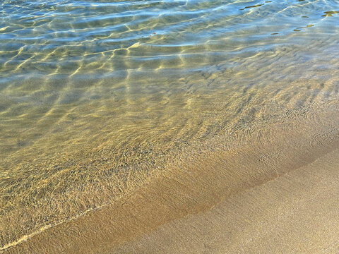 Gentle ocean waves on sand beach.